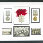 Framed medals in black and white mount, in a multi-aperture frame.