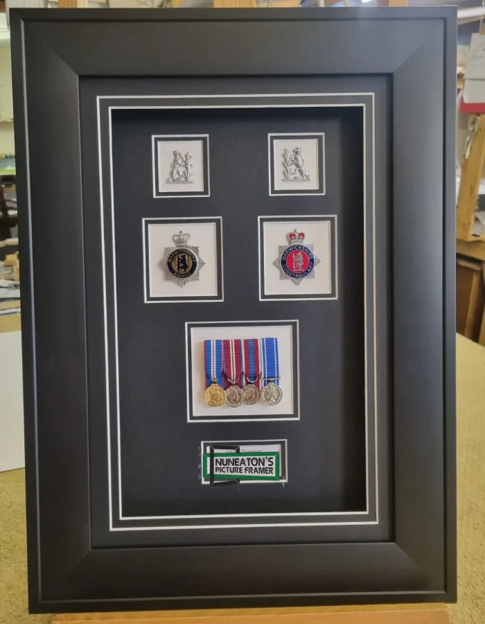 A custom-framed display featuring police force badges, service medals, and epaulettes with a dark mount.