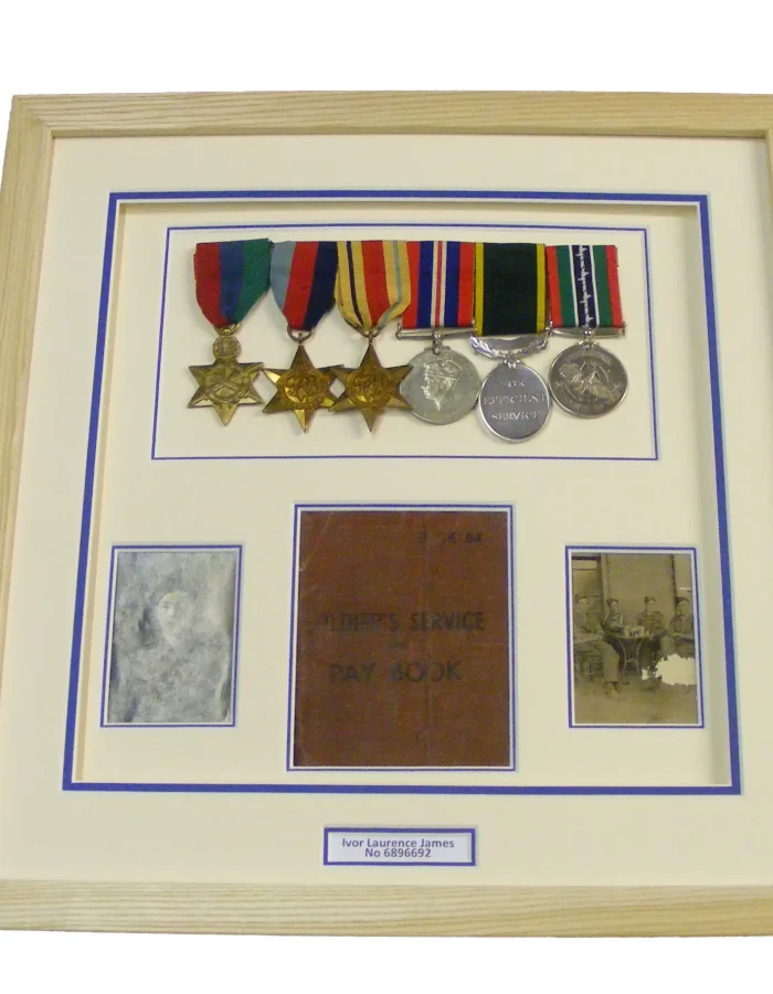 Custom military memorabilia framing featuring service medals, official badges, and certificates in a natural wood frame.